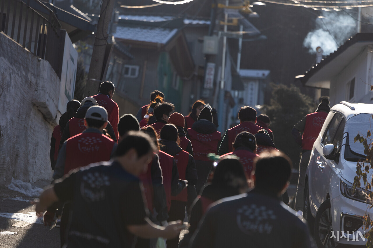2024년 12월24일 서울 서대문구 홍제동 개미마을에서 연탄은행 주최로 열린 ‘성탄 연탄데이’ 연탄나눔 행사에서 자원봉사자들이 연탄을 나르기 위해 이동하고 있다. ⓒ시사IN 이명익