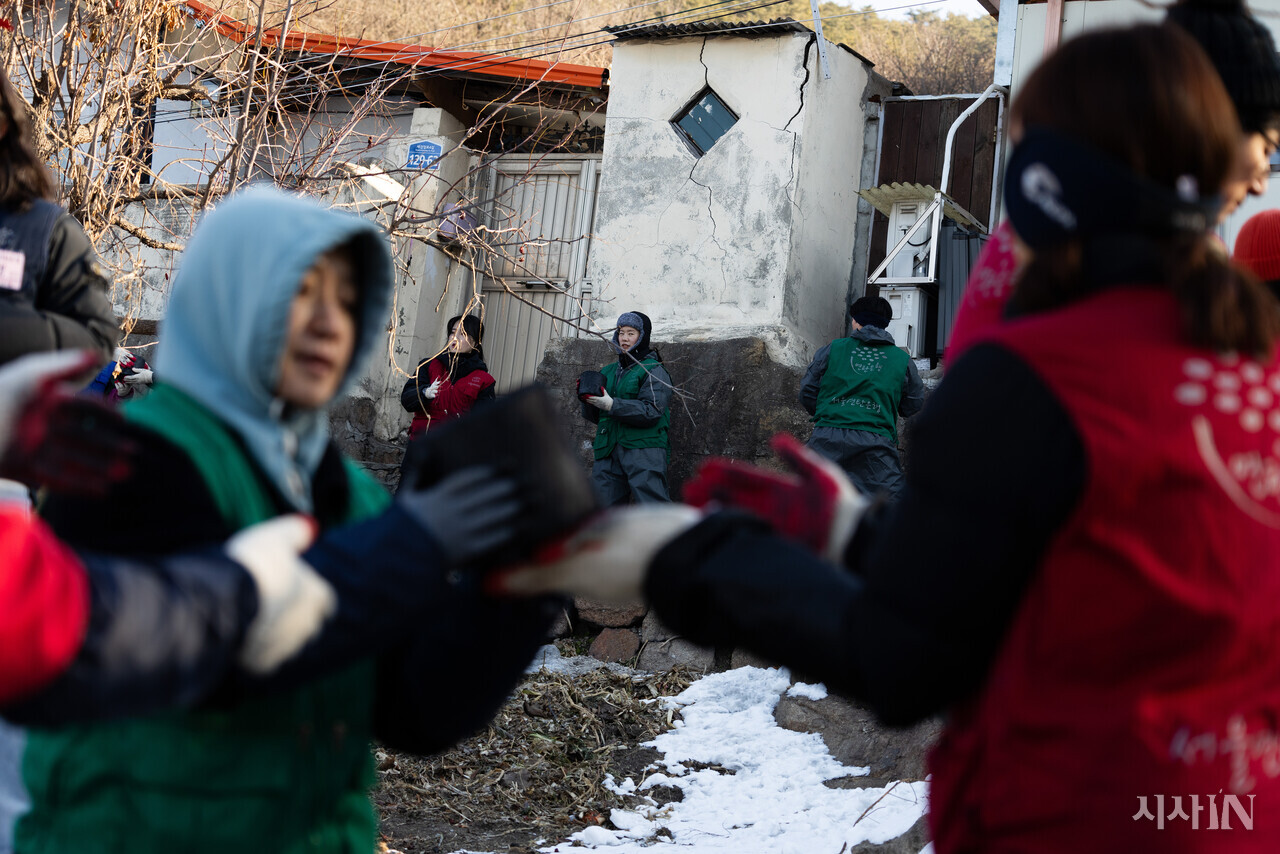 서울 서대문구 홍제동 개미마을에서 연탄은행 주최로 열린 ‘성탄 연탄데이’ 연탄나눔 행사에서 자원봉사자들이 손에서 손으로 연탄을 나르고 있다. ⓒ시사IN 이명익