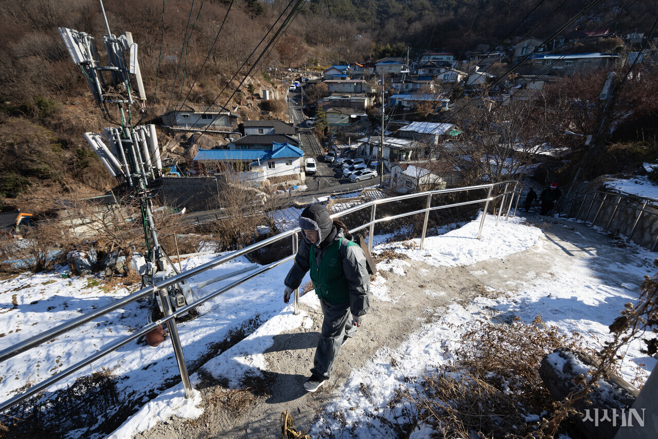 서울 서대문구 홍제동 개미마을에서 연탄은행 주최로 열린 ‘성탄 연탄데이’ 연탄나눔 행사에 참여한 한 자원봉사자가 연탄을 지고 마을을 오르고 있다. ⓒ시사IN 이명익