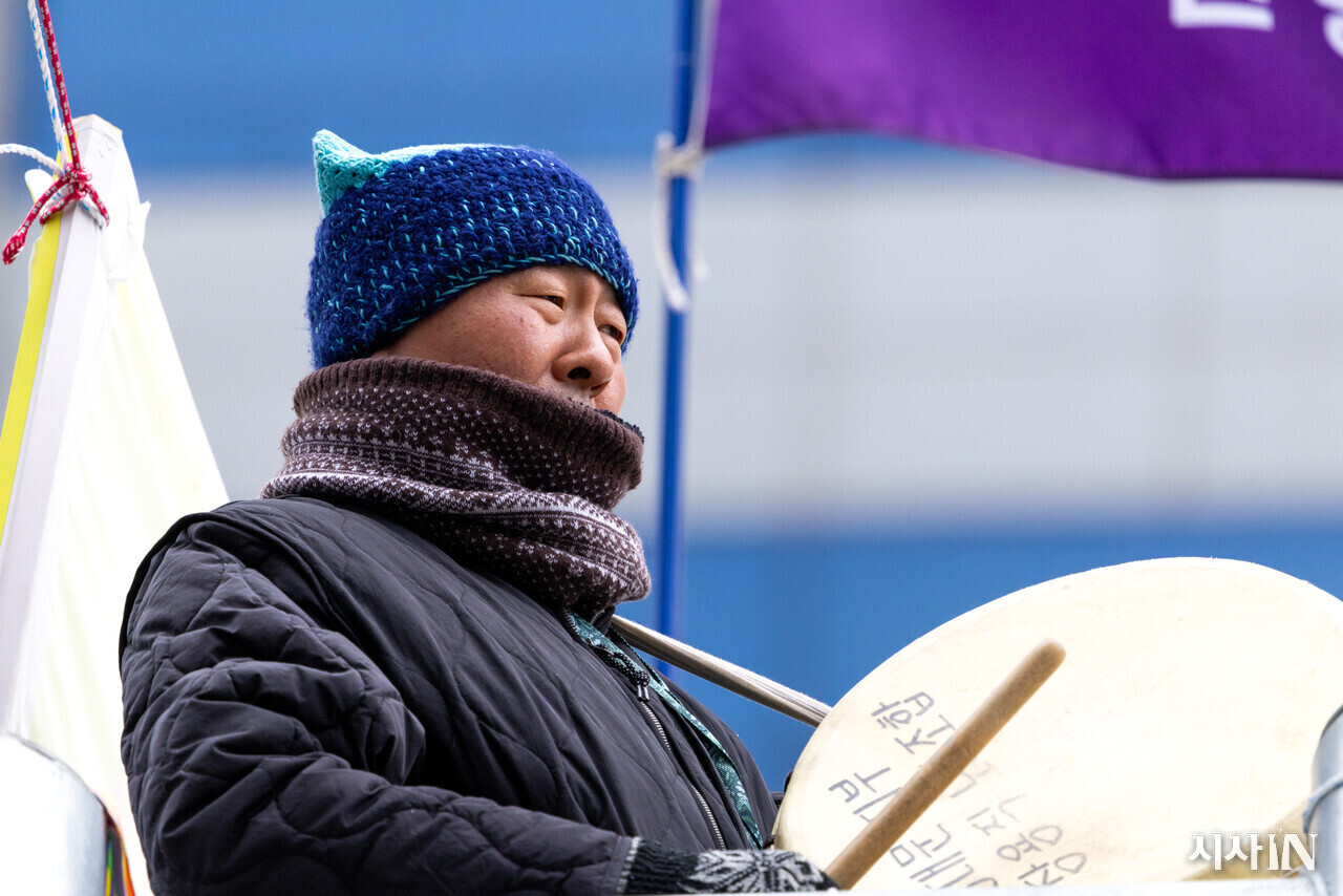 고진수 지부장이 세종호텔 앞 지하차도 위 철제 구조물 위에 서서 북을 두드리고 있다. ⓒ시사IN 신선영
