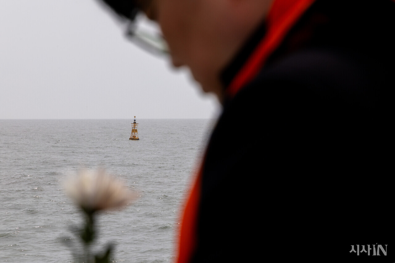 세월호 참사 해역에서 헌화하는 참석자 뒤로 ‘세월’ 부표가 떠 있다. ⓒ시사IN 신선영