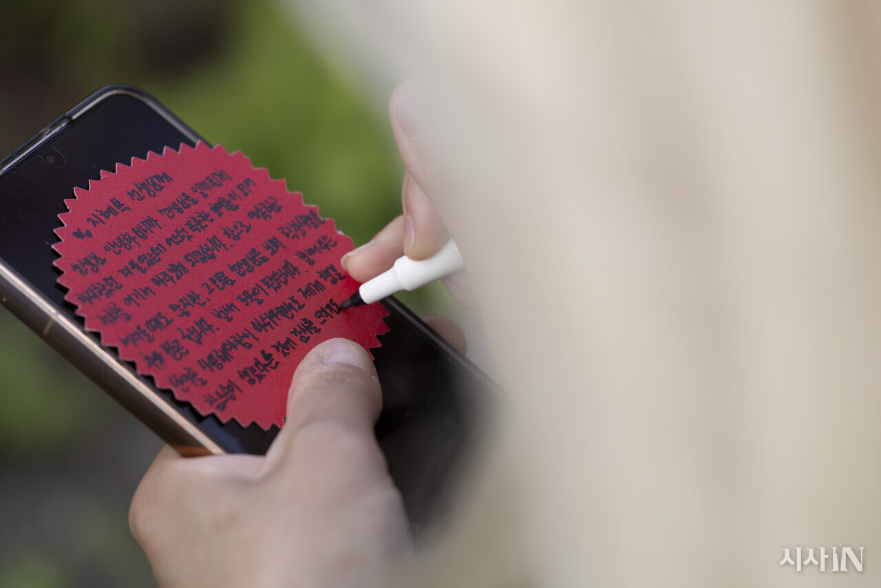집회 시작 전 연대차 방문한 참석자가 카네이션 메모지에 지혜복 선생님에게 보내는 글을 적고 있다. ⓒ시사IN 이명익