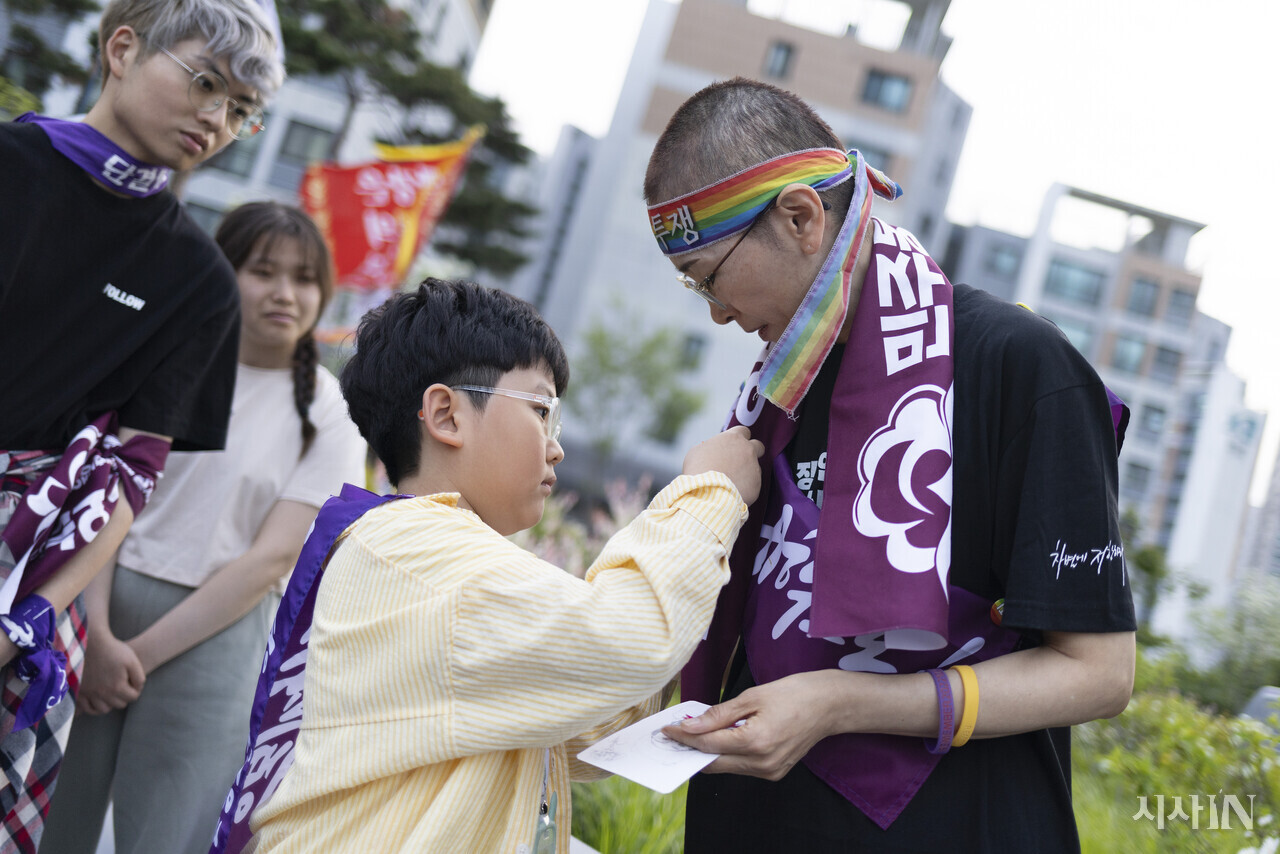 이날 집회에 참가한 김아준 군(9)이 지혜복 교사에게 직접 만든 종이 카네이션을 달아주고 있다. ⓒ시사IN 이명익
