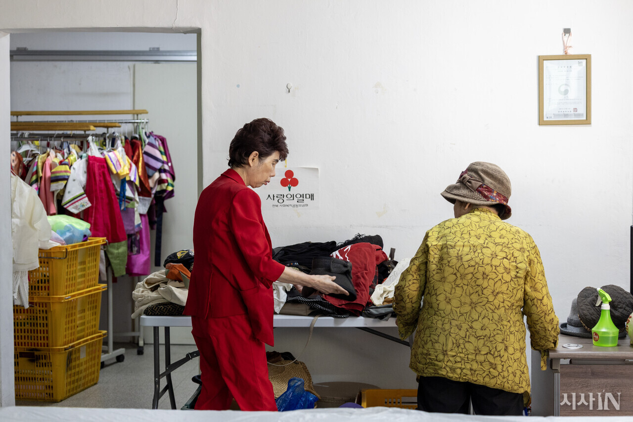김미선 원장이 동네 사람들에게 받은 구제 물품 중 모자 하나를 손님에게 1000원에 팔고 있다. 수익금은 사랑의 열매에 전액 기부한다. ⓒ시사IN 박미소