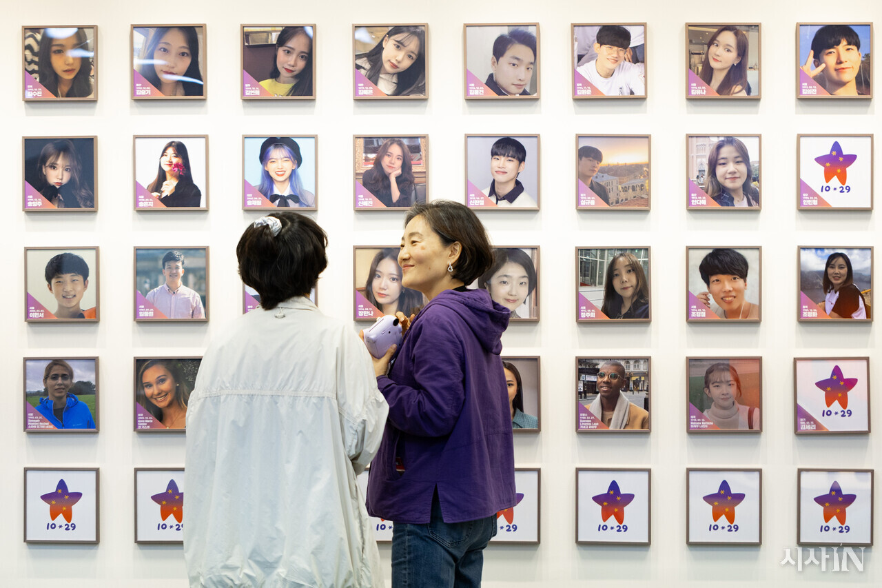 고 신애진씨의 어머니 김남희씨가 별들의 집을 찾은 시민 박지영씨에게 사진을 찍어준 후 희생자들의 영정사진을 함께 보고 있다. ⓒ시사IN 박미소