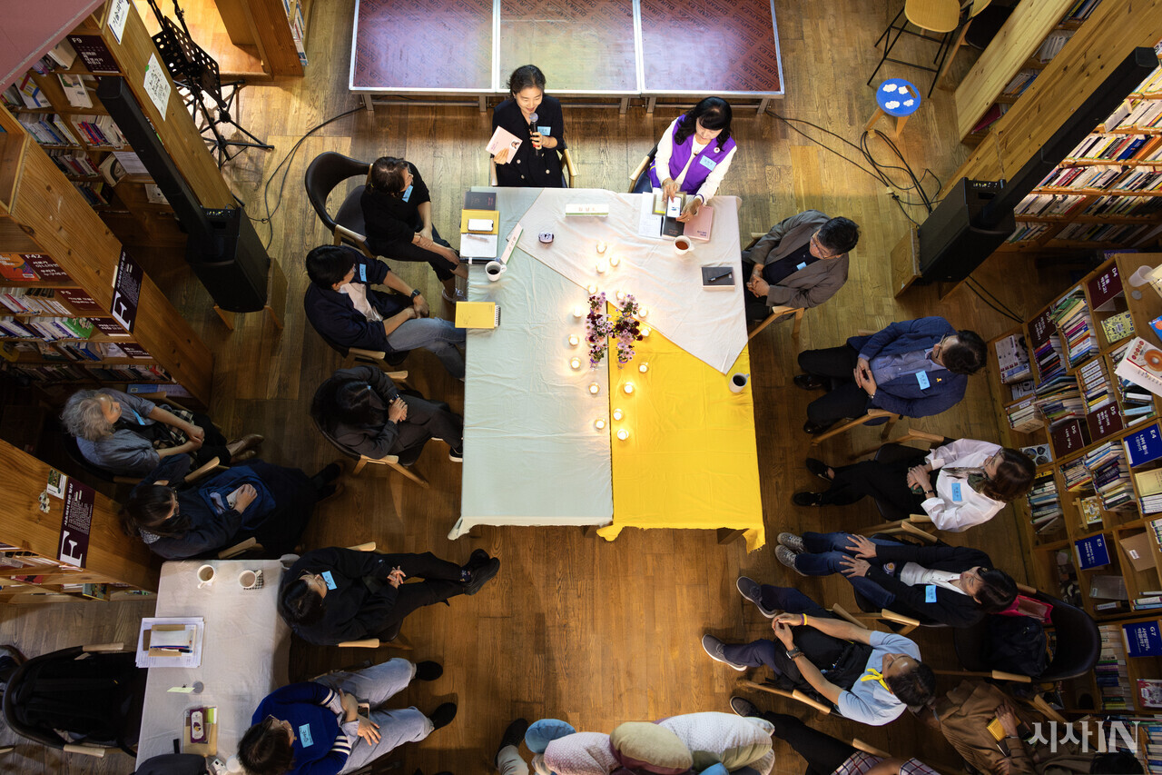 10월17일 경기 용인시 느티나무도서관에서 고 신애진씨의 어머니 김남희씨가  책을 들고 발언하고 있다. 그의 오른쪽에는 고 김의진씨의 어머니 임현주씨, 고 신애진씨의 아버지 신정섭씨가 앉아 있다. ⓒ시사IN 박미소