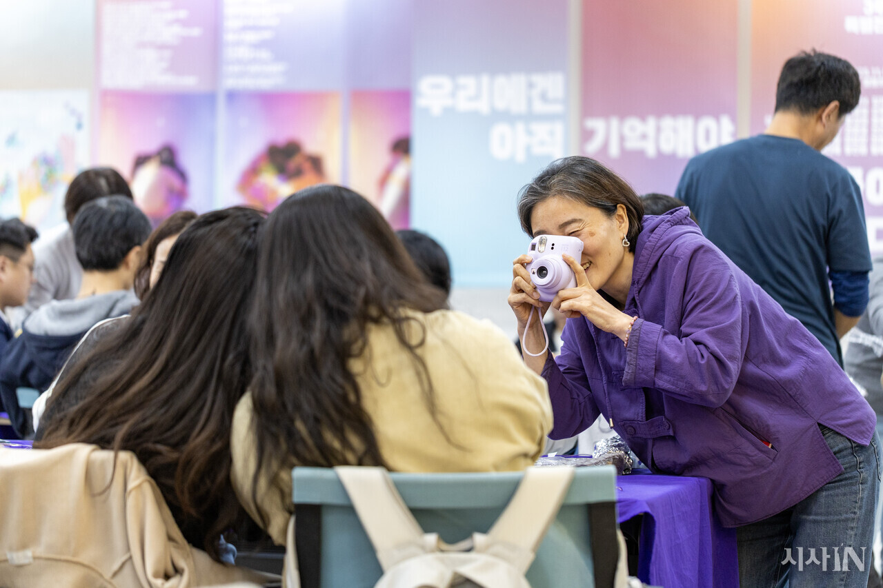 10월22일 서울 종로구 이태원 참사 추모 공간 ‘별들의 집’에서 고 신애진씨의 어머니 김남희씨가 참사 3주기를 맞아 열린 보라공작소를 찾은 시민들에게 사진을 찍어주고 있다. ⓒ시사IN 박미소